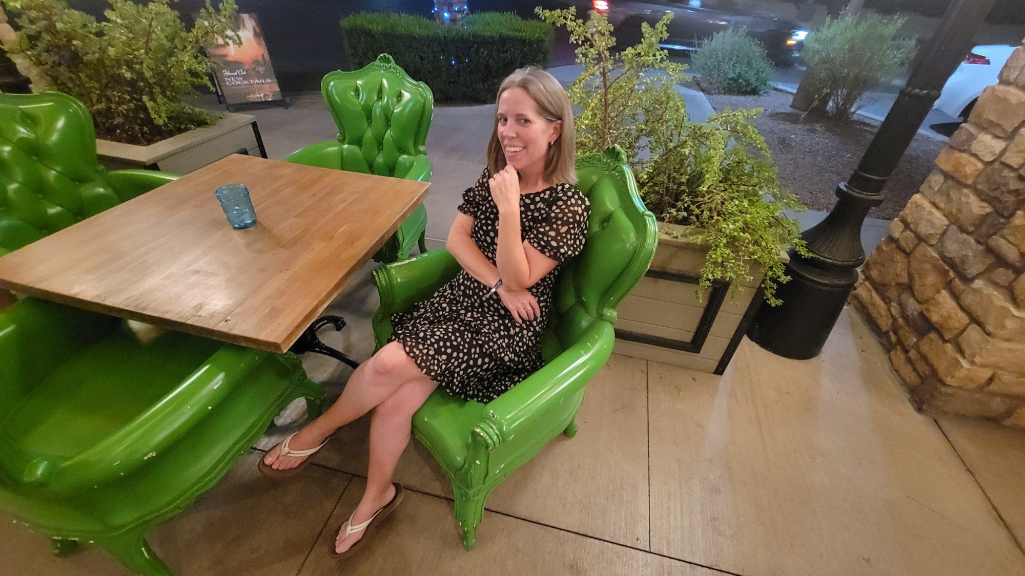 Georgia smiling in a bright green armchair on a restaurant patio